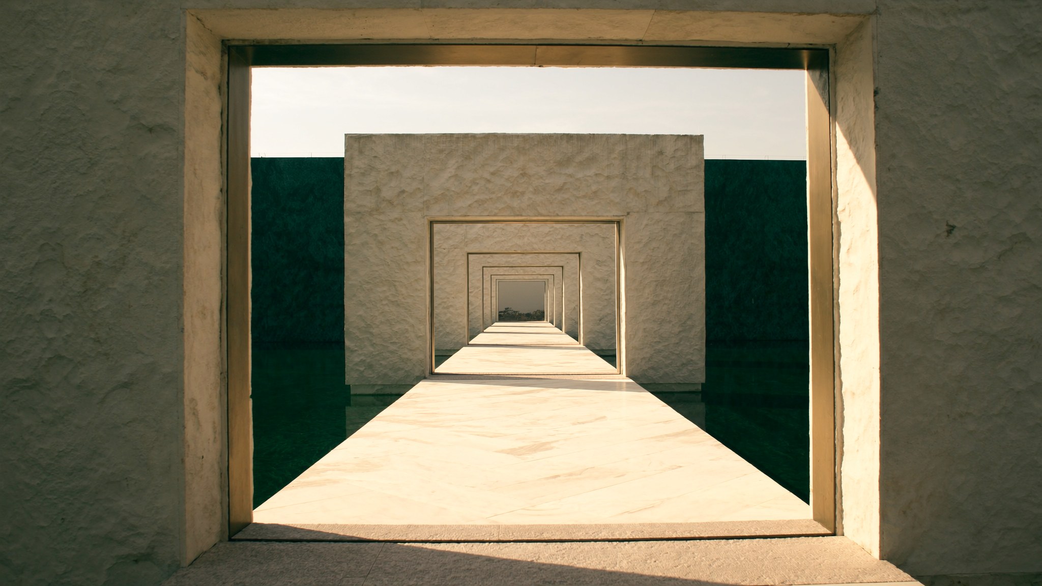 An imagined gallery of limestone portals extending into deep green reflections